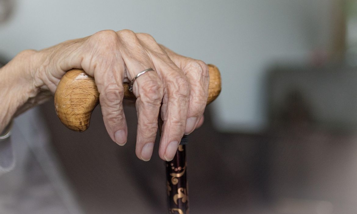 Mano di donna anziana che mantiene un bastone, in solitudine della terza età.